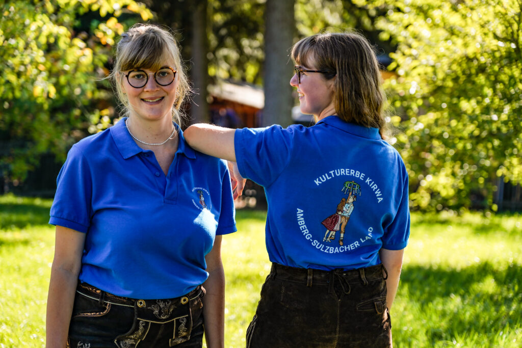 Zwei Frauen posieren mit blauen T-Shirts in der Natur.